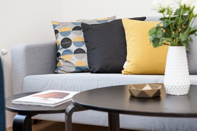 a grey couch with black and yellow throw pillows